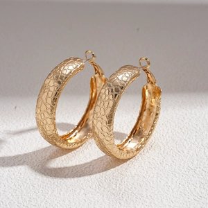 Close-up of golden round hoop earrings featuring a unique crackle texture finish