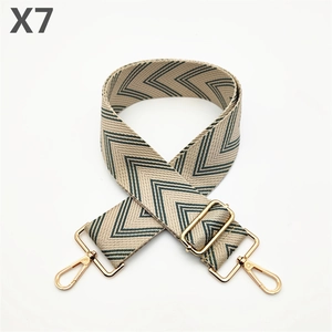 Macro detail of wide adjustable bag strap with green V-pattern and gold metal buckles