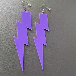 Close-up of purple acrylic lightning bolt drop earrings with secure metal hooks