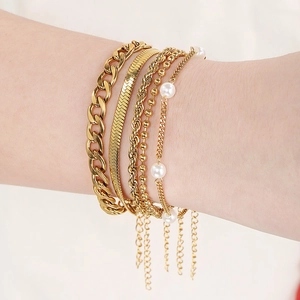 Five-piece gold layering bracelet set featuring snake, twist, bead and pearl chains