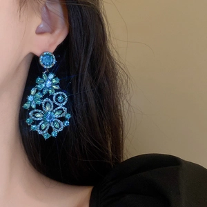 Detail view of vintage blue flower crystal drop earrings worn on a female model