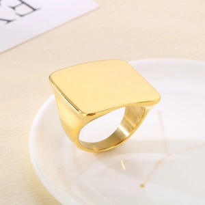 Detail of a square gold signet ring with a polished mirror finish on a ceramic tray