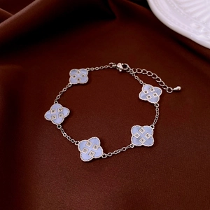 Detail of light blue enamel clover bracelet with silver chain on silk fabric background