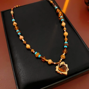 Detail of bohemian heart pendant necklace with amber stone and colorful beaded chain