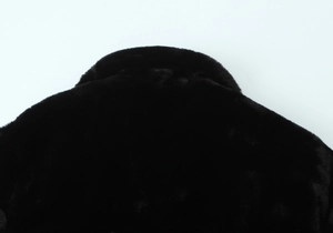 Gros plan du col en peluche et de la texture du dos d'une veste en fausse fourrure noire