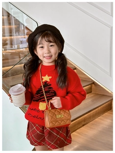 Close-up of child wearing a red Christmas sweater and brown quilted chain crossbody bag