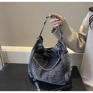 Détail du sac cabas en denim noir délavé avec bords effilochés au style vintage