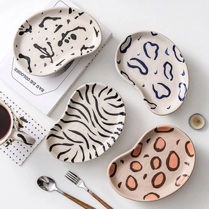 Hand-painted ceramic plates with zebra and leopard prints in irregular bean shapes