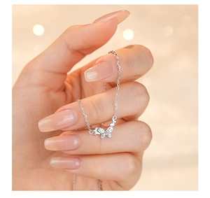 Close-up of hand holding a silver butterfly pendant necklace with sparkling zircons