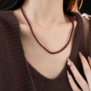 Close-up of anchor red beaded necklace on model neck for retro fashion styling
