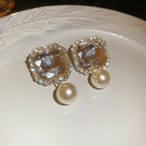 Detail of vintage gold earrings with square zircon and elegant white pearl drop