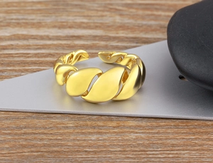 Detail of 18K gold plated twisted irregular ring on a minimalist stone background