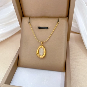 Minimalist gold titanium necklace with teardrop cat eye stone on white silk background