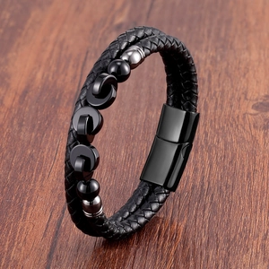 Close-up of black braided leather bracelet with metal beads and magnetic clasp on wood