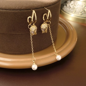 Détail de boucles d'oreilles tulipes dorées avec zircon scintillant et perles pendantes