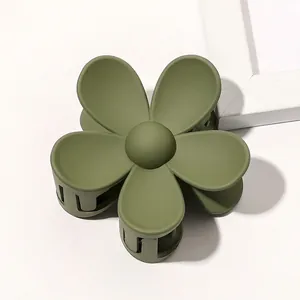 Detail of matte olive green flower hair claw clip with interlocking teeth for styling