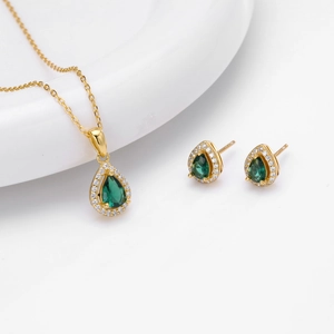 Detailed set of gold necklace and drop earrings with green zircon and diamond accents