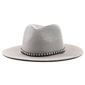 Detail of light gray straw fedora hat featuring a black leather band with silver metal studs