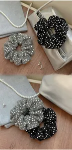 Detail view of shimmering sequin scrunchies set in black and silver metallic fabric