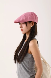Vue latérale d'un béret rose en coton avec broderie cursive porté par un mannequin
