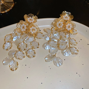 Detailed view of floral pearl earrings with long white tassels and golden metal outlines