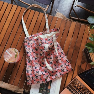 Detail of vintage floral cotton tote bag with pink rose patterns and woven shoulder straps