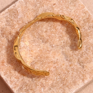 Close-up of gold plated stainless steel bangle with irregular hammered wave texture