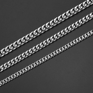 Set of three silver Cuban link chains in varying widths on dark professional background
