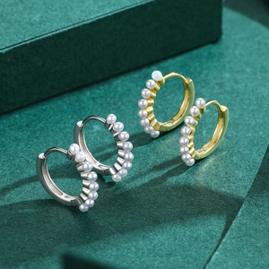 Elegant s925 silver and gold plated pearl hoop earrings set on a dark green surface