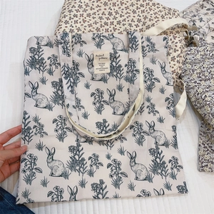 Detail of floral rabbit pattern and fabric label on a beige canvas tote bag