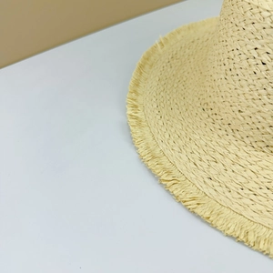 Detailed macro view showing the fine straw weave texture and frayed edges of the sun hat