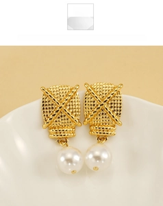 Detail view of gold woven texture earrings with white pearl drops on a ceramic bowl
