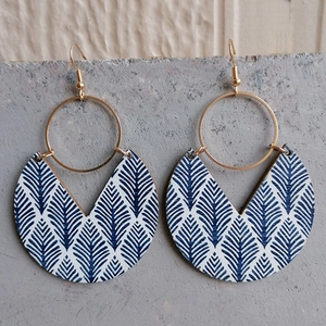 Detail of bohemian gold hoop earrings with blue and white patterned wooden crescent pendants