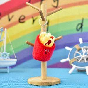 Cute plush french fry keychain charm hanging on a wooden display stand