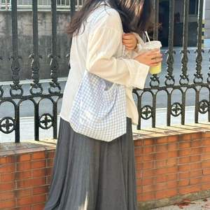 Outdoor lifestyle shot of a large light blue checkered canvas tote bag with casual outfit