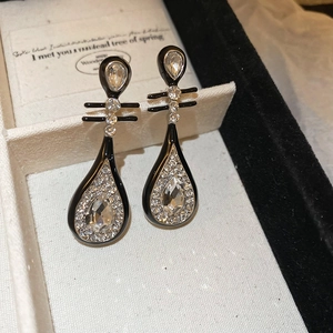 Detailed close-up of teardrop black and white crystal drop earrings in a jewelry box