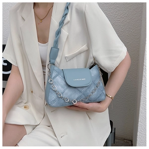 Detail of light blue denim textured shoulder bag with metal chain and leather strap on a model