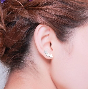 Minimalist silver star cluster stud earrings worn by a model in a close-up shot