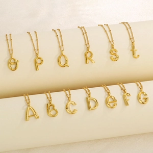 Detailed view of bold 3D golden initial letter pendants on delicate bead chains
