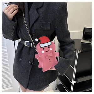 Pink gingerbread man crossbody bag with gold chain shown on dark blazer outfit
