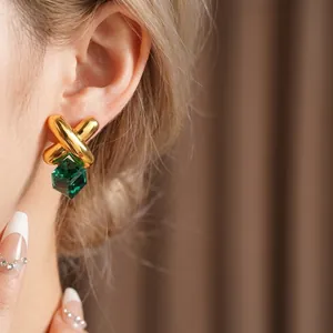 Vintage gold criss-cross earrings with emerald green cube crystal on a model