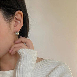 Detailed close-up of a silver-grey pearl earring on a model's ear for an elegant look