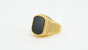 Detail of gold titanium steel ring with black obsidian stone and grid engraved pattern