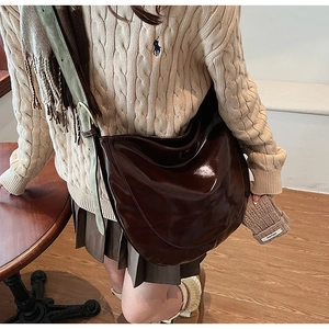 Detail of a large brown hobo bag in glossy oil wax leather with adjustable wide strap