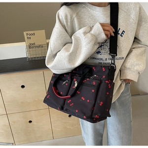 Detail of cherry print tote bag featuring dual front zip pockets and red handle