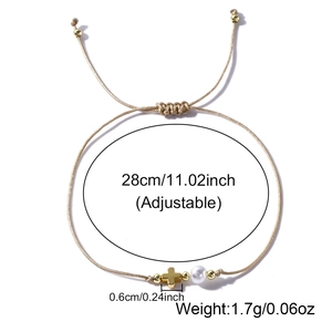 Detail view of gold braided bracelet with cross pendant and pearl showing 28cm adjustable size