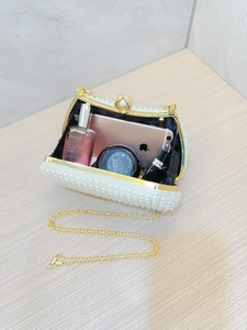 Elegant white pearl clutch bag with gold chain strap, showing interior storage space