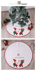 Detail of white Christmas tree skirt with plush gnomes and Merry Christmas script