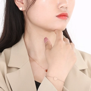 Close-up of minimalist rose gold heart necklace and earrings set worn by a model