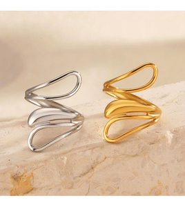Close-up of wavy gold and silver stainless steel rings on a beige stone surface